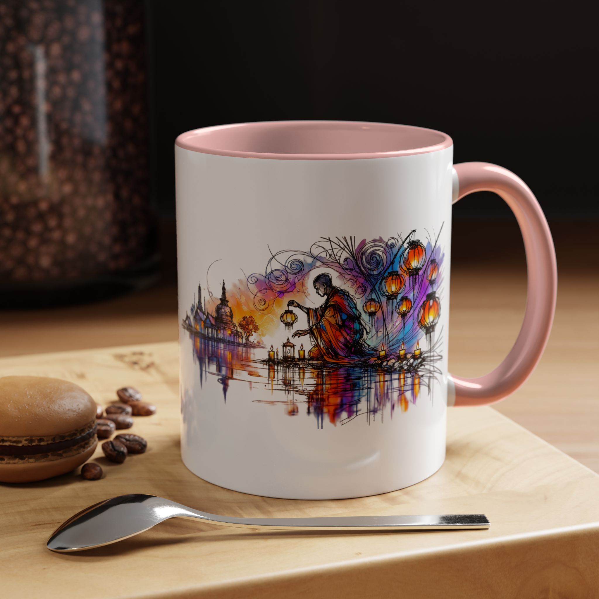 Mug with a colorful artistic design featuring a figure and lanterns, placed on a wooden surface with a macaron and spoon.
